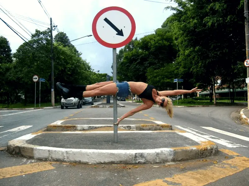 Street pole dancing: a woman performs a #poledancing trick on a street sign in the middle of the road. #PoleFitness