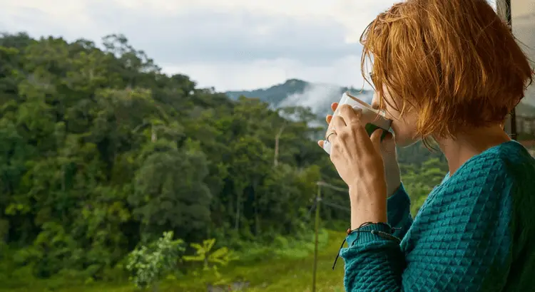 Woman drinking from a mug looking at nature