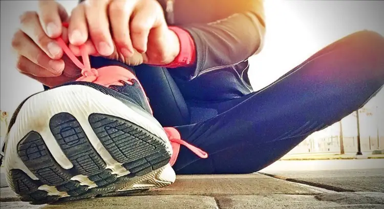 Person stretching their lower leg with running shoes on